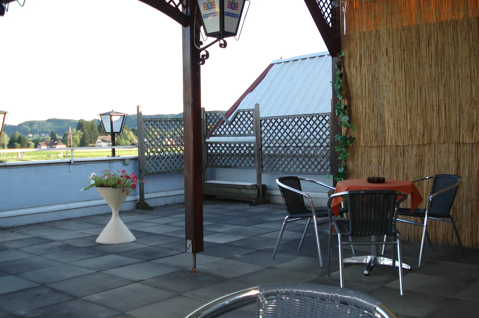 Terrasse des Cafes mit Tischen, Stühlen und Blick ins Grüne