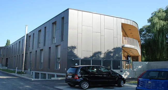 Gebäude mit grauer Plattenfassade und vorgesetzten Holzbalkonen