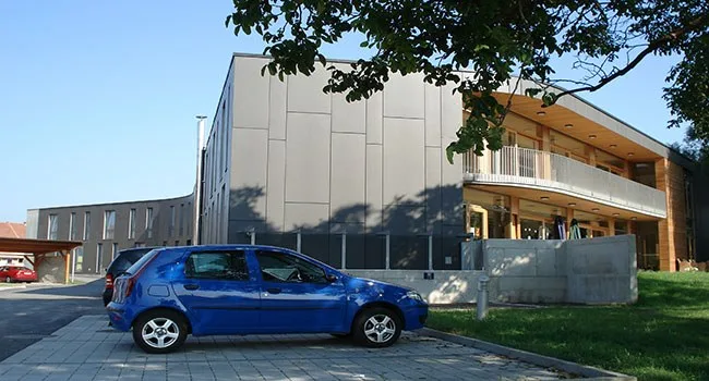 Wohnbau mit grauer Fassade und Zufahrt, Ansicht von der Straße