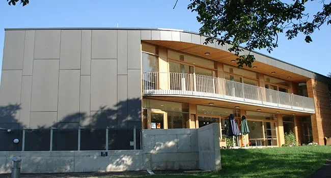 Wohnbau mit grauer Plattenfassade und umlaufendem Holzbalkon