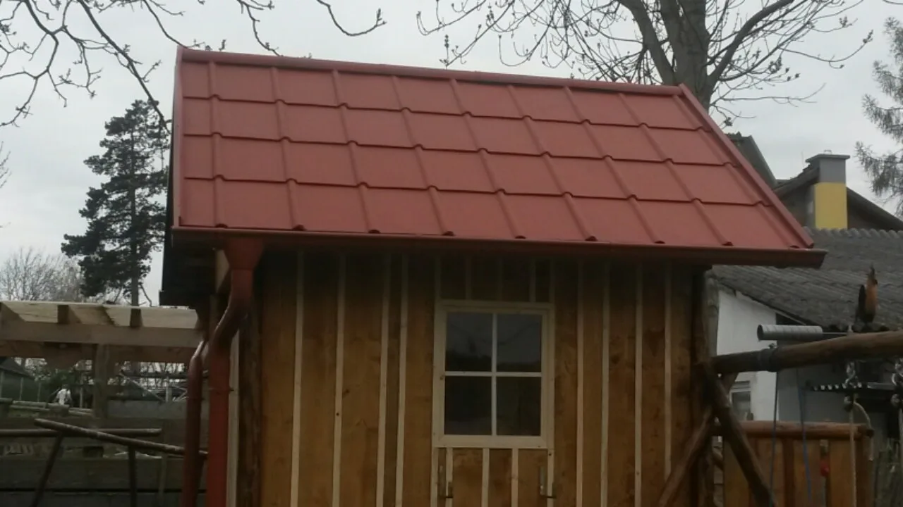Gartenhütte aus Holz mit rotem Prefa-Dach und Regenrinne
